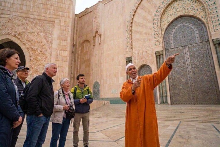 A group of people standing in front of a building with intricate architectural details. 1