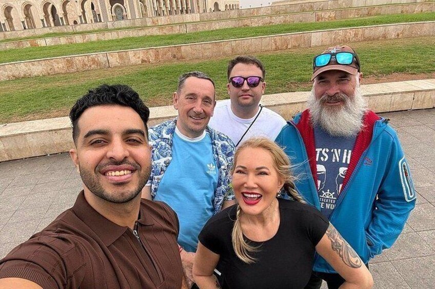 A group of people taking a selfie in a public square with a historical monument in the background. 1