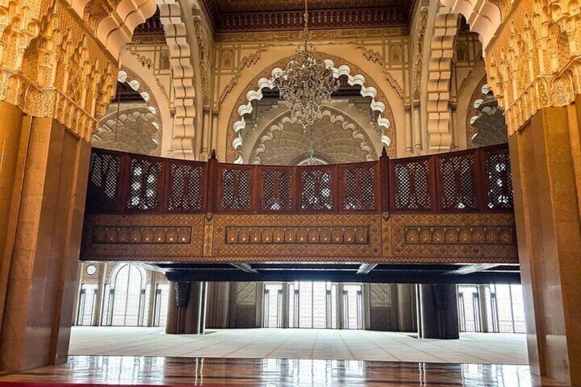An ornate interior with arches, a wooden balcony, and a chandelier. 2