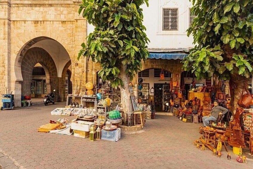 A market area with stalls, a tree, and a building with arches. 3