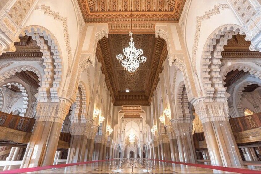 An ornate interior with arches, columns, and a chandelier. 3