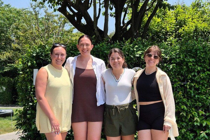 Four people standing outdoors with a tree and greenery in the background. 4