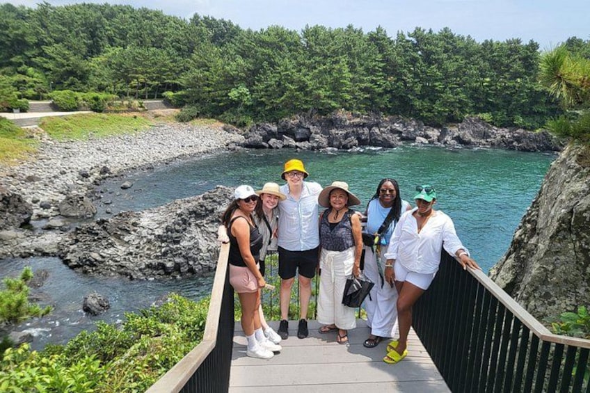 A group of people on a wooden bridge overlooking a river with rocky banks and lush greenery in the background. 3