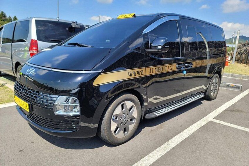 A black van with 'Jumbo Taxi' written on the side parked in a lot. 2