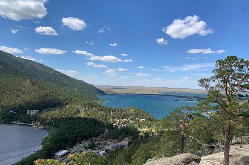 Ein See, umgeben von Bergen, ein klarer Himmel und einige Gebäude in der Nähe des Ufers. 1