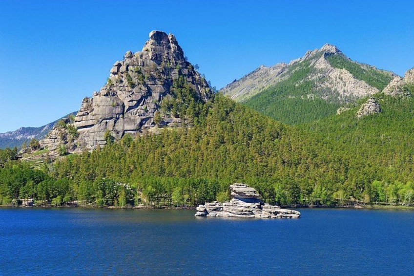 Ein Berg mit felsigem Gipfel, ein bewaldetes Gebiet und ein Gewässer mit einer kleinen Insel. 5