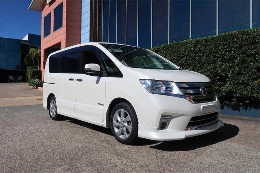 A white minivan parked in front of a modern building with a blue and red facade. 5