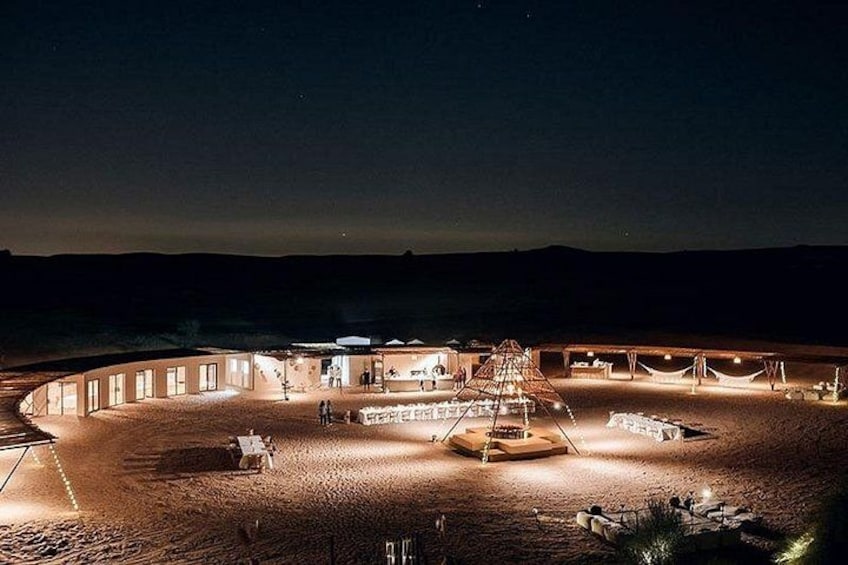A circular building with multiple rooms and a central open area, surrounded by a sandy landscape. 5