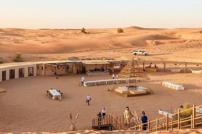 A desert camp with tents, a pyramid structure, and a white pickup truck. 3