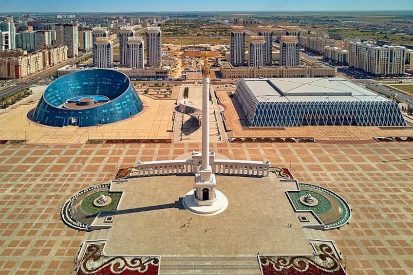 A large circular building, a central monument, and surrounding high-rise buildings. 4