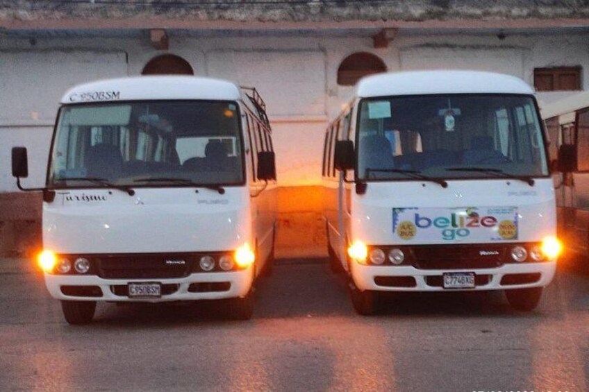 Two white vans with 'Belize Go' branding on the front, parked side by side on a road. 4