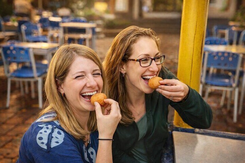 Two people sitting at an outdoor cafe, eating food. 2