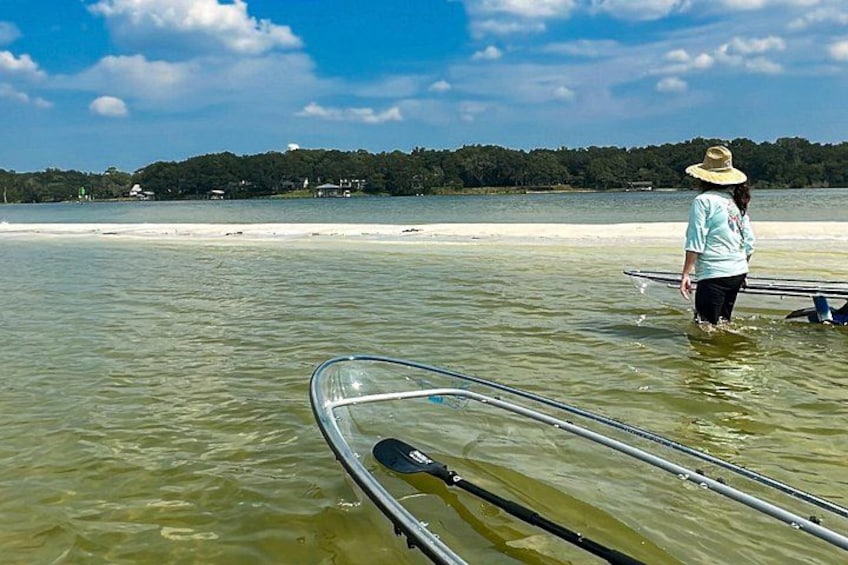 A person in a hat standing in shallow water with a kayak. 2