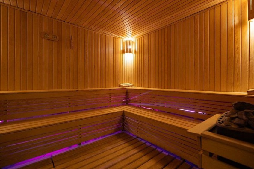 A wooden sauna with benches and a central light fixture. 3