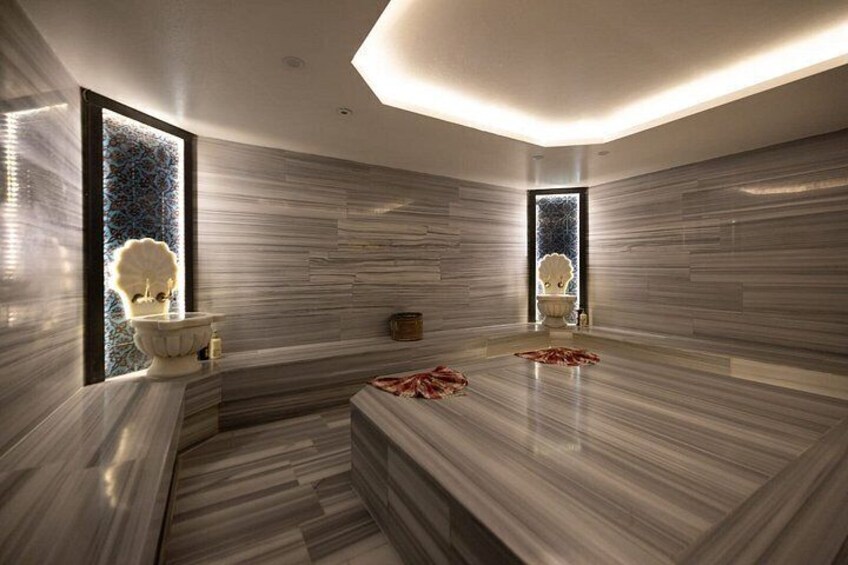 A modern bathroom with a marble floor, a large bathtub, and a window with a decorative view. 4