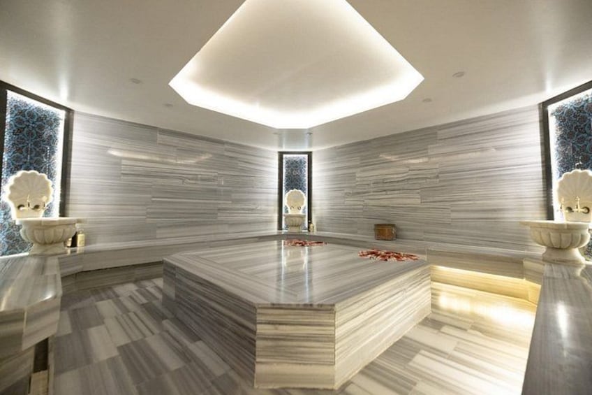 A modern bathroom with a central marble sink, large windows, and decorative shells. 5