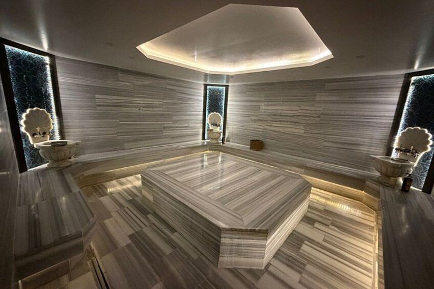 A modern interior with a large marble-topped table, sleek white walls, and decorative lighting fixtures. 1