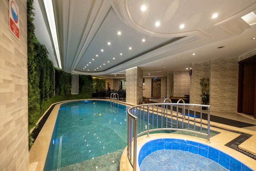 An indoor swimming pool with a curved design, surrounded by tiled walls and a glass barrier. 4
