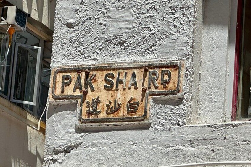 A weathered street sign with 'PAK SHARD' and another language. 4