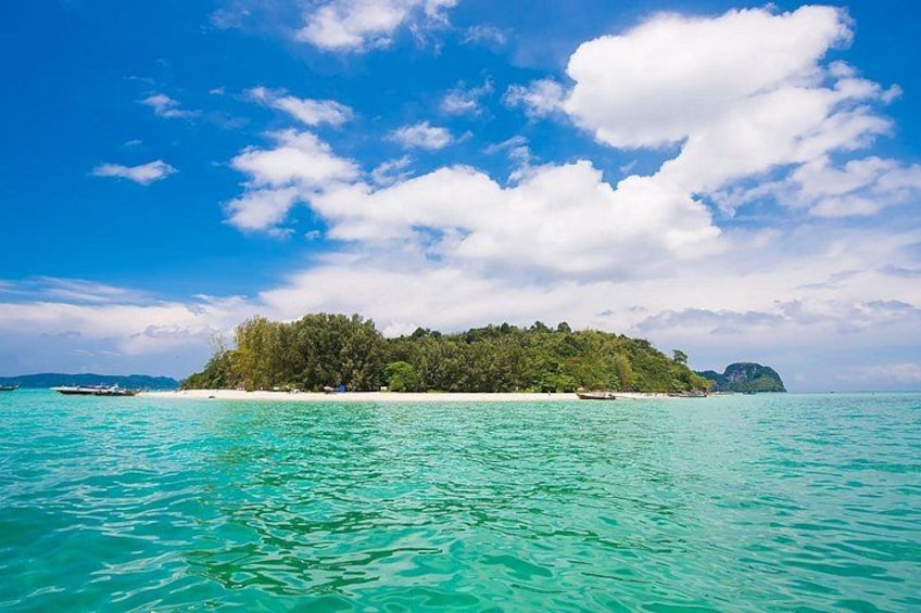 Une mer turquoise, une petite île parsemée d’arbres et un ciel d égagé. 1