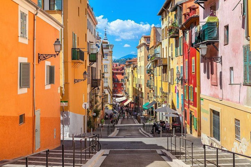 Una stretta via fiancheggiata da edifici colorati, un attraversamento pedonale e una vista in lontananza di una montagna. 1