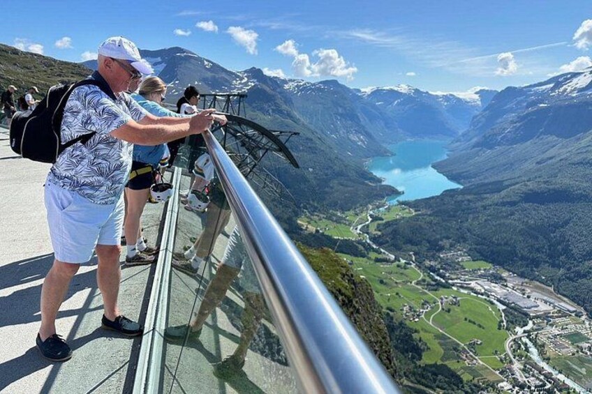 En person som fotograferar en sjö som omges av berg. 3