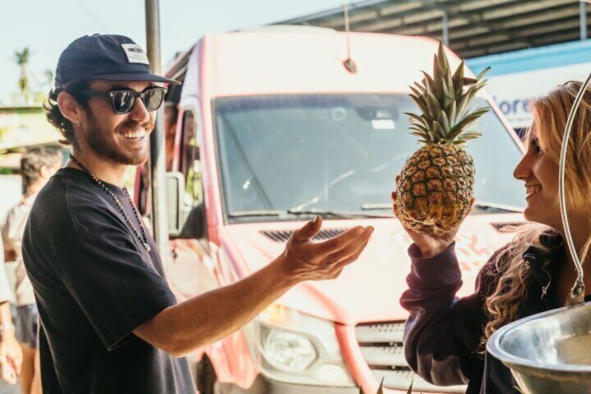 A person holding a pineapple near a vehicle. 4
