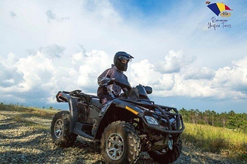 Une personne conduisant un quad sur un chemin de gravier, sous un ciel nuageux. 1