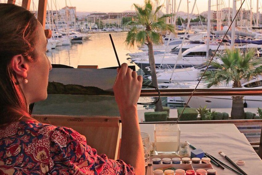 A person painting with a view of a marina and boats. 1