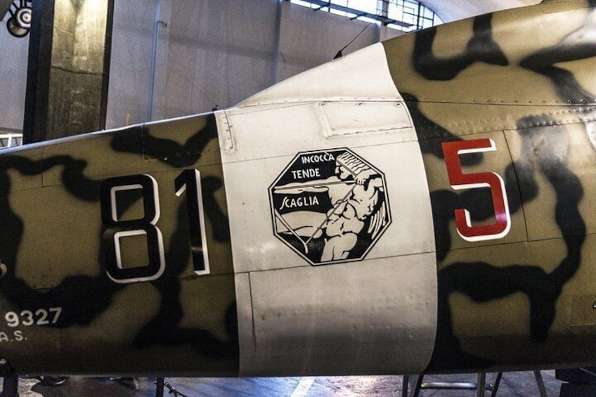 A military aircraft with camouflage paint, the number 81, and a logo with 'INCOCCA TENDE' and 'SCAGLIA' on its side. 1