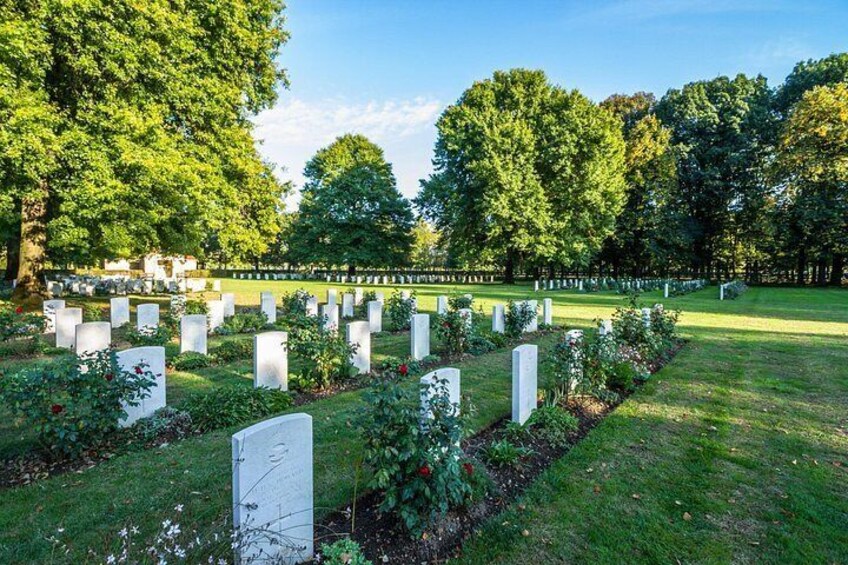 A cemetery with rows of headstones, surrounded by trees and grass. 2