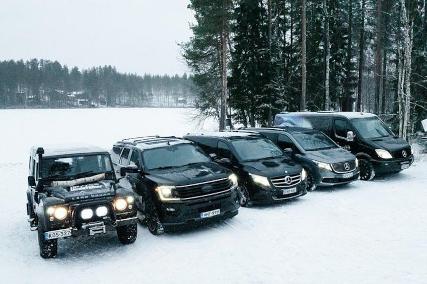 A line of black vehicles parked on a snowy surface with trees in the background. 3