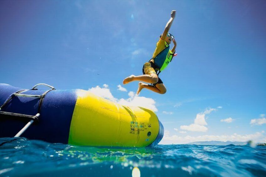 A person jumping off a yellow and blue inflatable device into the ocean. 2