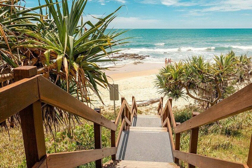 A wooden staircase leading to a beach with palm trees and ocean waves. 3