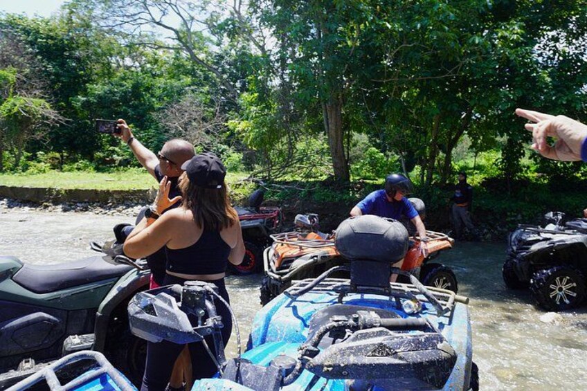 Menschen fahren mit Quads nahe einem Fluss, umgeben von Bäumen. 2