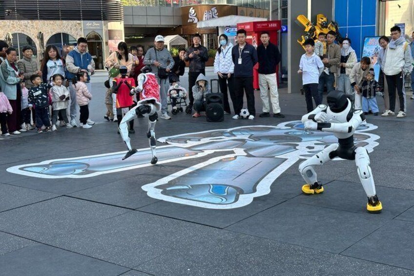 A street performer with a robot-like figure and a child interacting in a public square. 2
