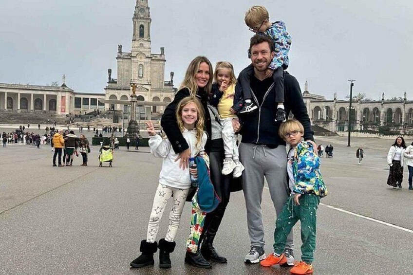 Una familia de cuatro personas en una plaza pública con un edificio histórico al fondo. 5