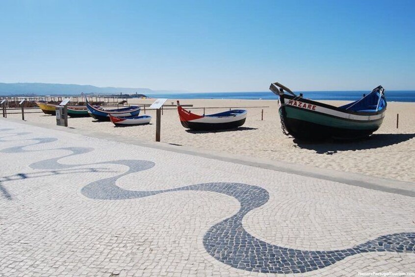 Une plage avec des bateaux et une promenade bordée de carreaux. 2