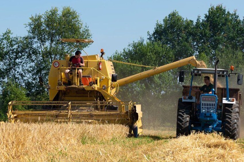 En skördetröska på ett fält, med en traktor i närheten. 3