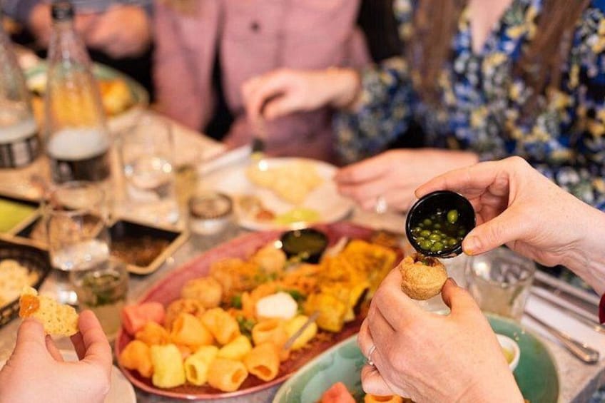 Personas comiendo, con comida y bebidas sobre la mesa. 3
