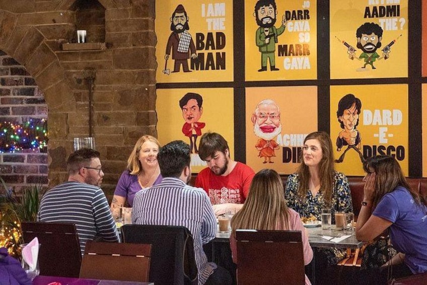 Un grupo de personas sentadas en una mesa en un restaurante con carteles de dibujos animados en la pared. 2