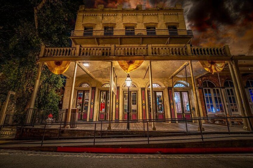 A historic building with a balcony, arched windows, and a central entrance. 3