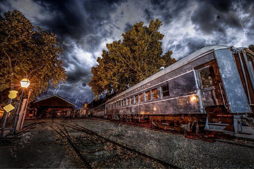 A vintage train at a station with lightning in the sky. 1