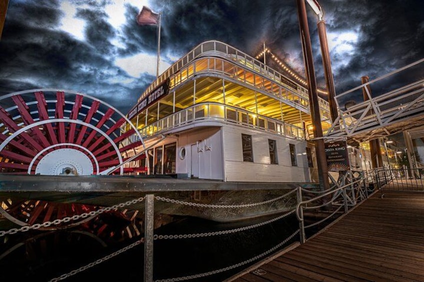 A cruise ship with a white and yellow building, a red and white wheel, and a wooden deck. 5