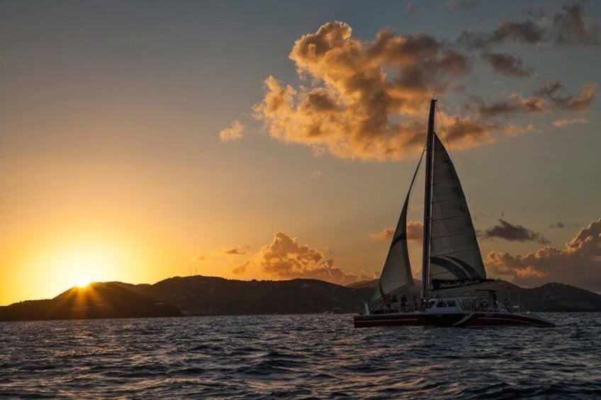 Un velero en aguas tranquilas durante la puesta de sol, con un cielo despejado y montañas distantes. 5
