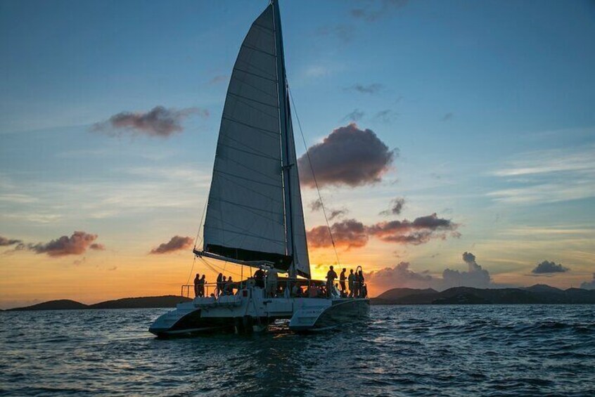 Un velero con una vela grande sobre aguas tranquilas al atardecer. 1
