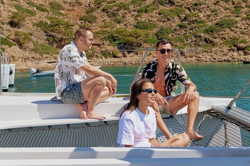 Three people sitting on a boat with a rocky shoreline in the background. 3