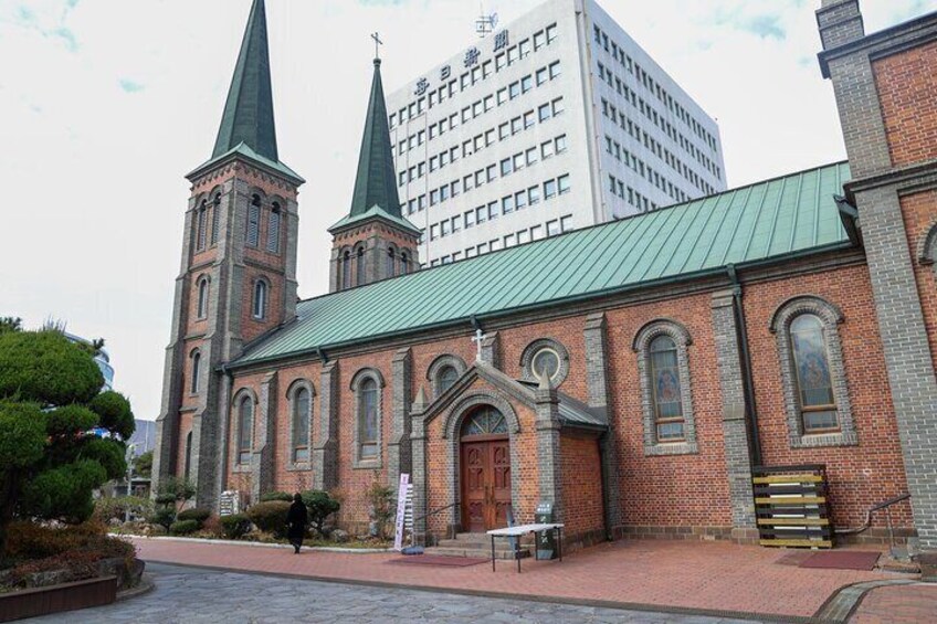 A historic church with two spires, a brick facade, and a green roof. 3