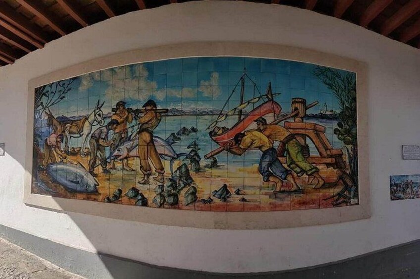 A mural depicting a fishing scene with people, a boat, and fish. 5