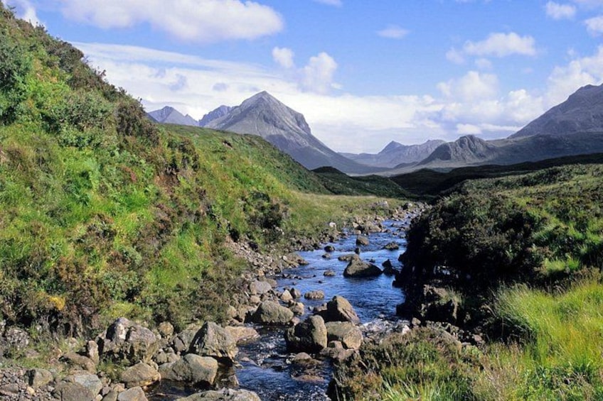 A river flowing through a mountainous landscape with rocky terrain and green vegetation. 4